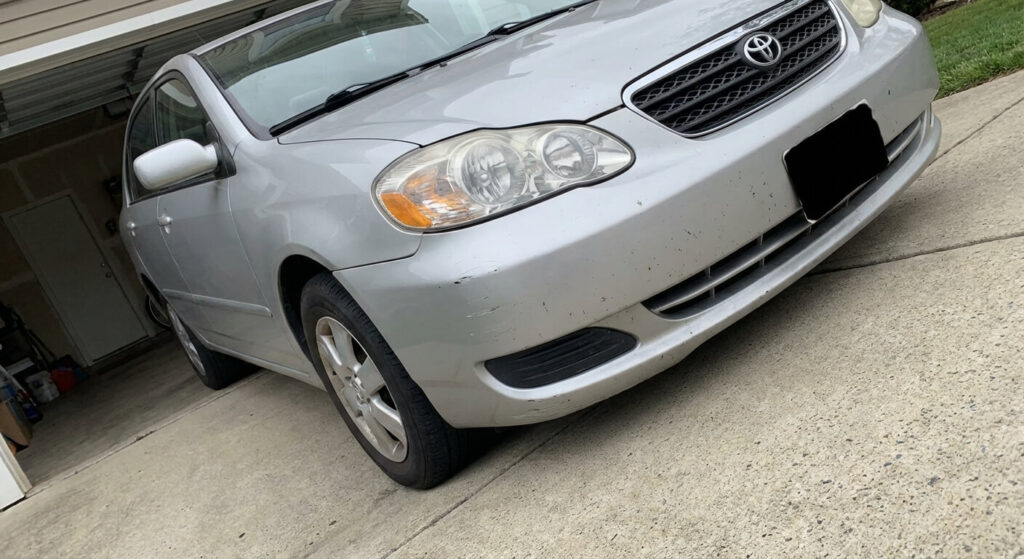 Voiture frottant son pare-choc avant sur une descente de garage trop pentue.
