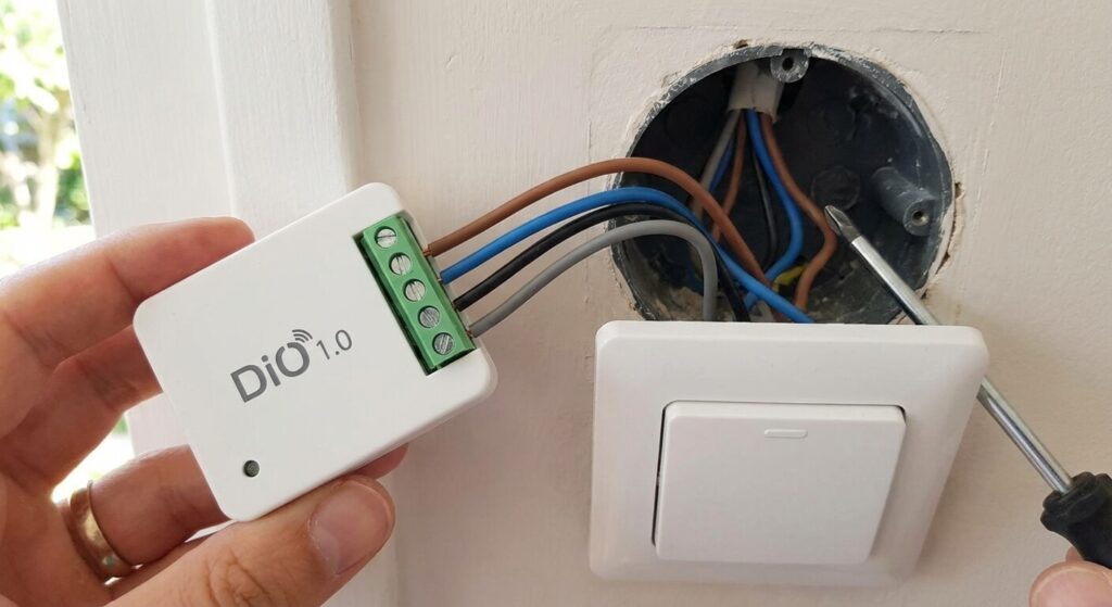 Petit module domotique DiO 1.0 blanc avec ses borniers à vis, prêt à être encastré derrière un interrupteur existant pour rendre l'éclairage intelligent