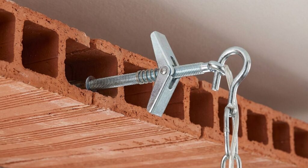 Cheville à bascule (type ressort) idéale pour fixer un lustre dans un plafond en brique creuse, garantissant un maintien par l'arrière de la paroi