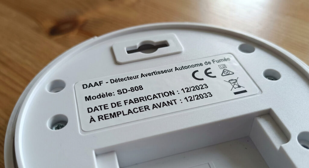 Vue arrière d'un DAAF (Détecteur Avertisseur Autonome de Fumée) montrant l'étiquette avec la date de fabrication et la date de remplacement obligatoire