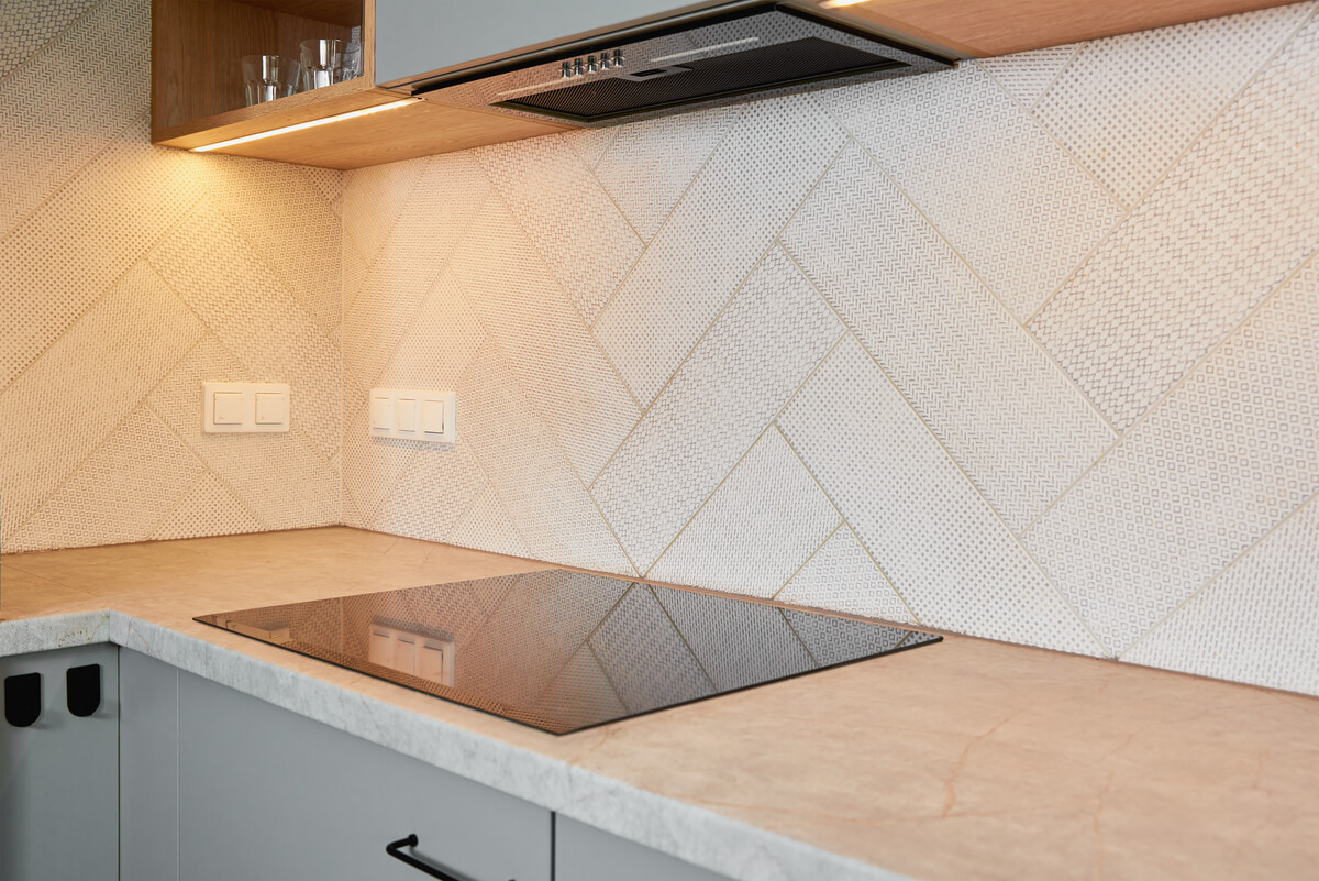 Une crédence en carrelage moderne protégeant le mur d'une cuisine lumineuse au-dessus du plan de travail.