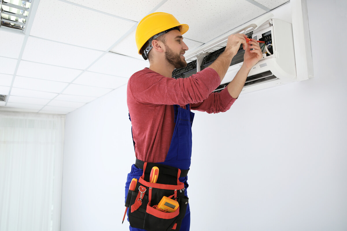 Un technicien frigoriste certifié installant une unité murale de climatisation dans une habitation à Liège.