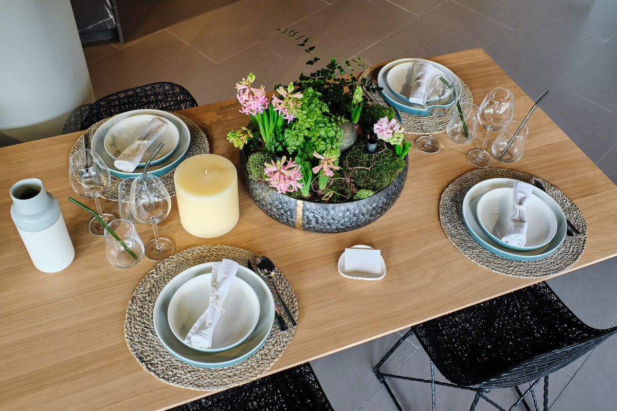 Assiettes et couverts dressés directement sur le plateau brut d'une table en chêne massif.