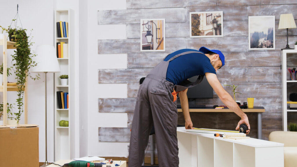 Aménagement intérieur sur mesure : comment trouver le bon spécialiste pour votre projet ? 3 Un menuisier professionnel ajustant les finitions d'un dressing sur mesure dans une chambre.