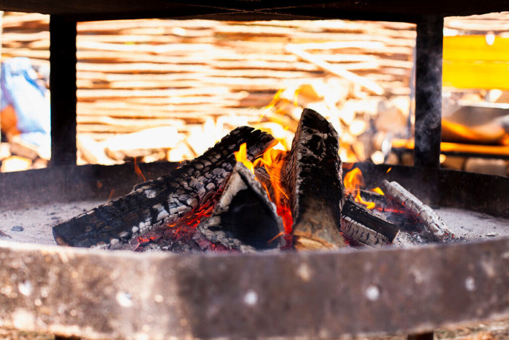 Un foyer de cheminée ouvert où de petits morceaux de suie noire et calcinée sont tombés sur la grille.