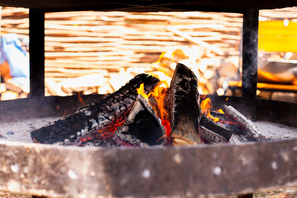 Un foyer de cheminée ouvert où de petits morceaux de suie noire et calcinée sont tombés sur la grille.