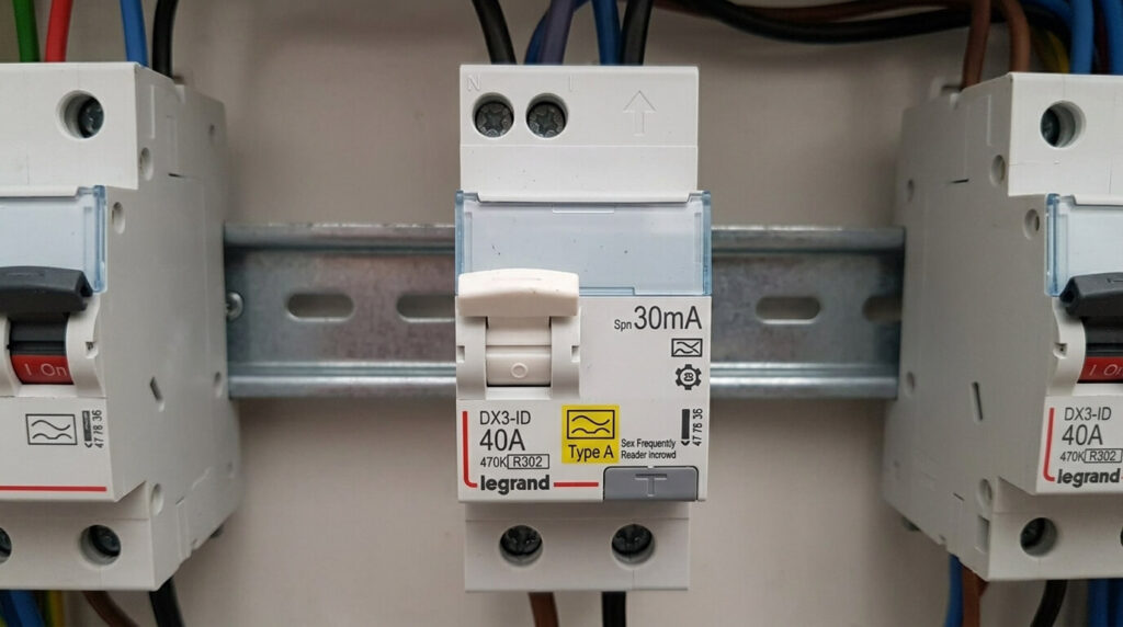 Gros plan sur le logo d'un interrupteur différentiel de type A installé sur un rail de tableau électrique.