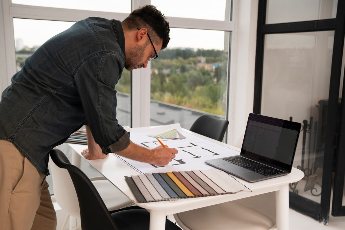 Un architecte d'intérieur dessinant des plans de mobilier sur mesure sur sa table de travail.