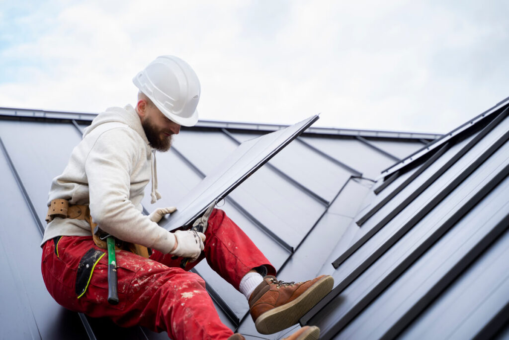 Toiture métallique à Laval : un investissement qui traverse les hivers québécois 3 Des couvreurs professionnels installant des panneaux de toiture en acier sur le toit d'une propriété québécoise.
