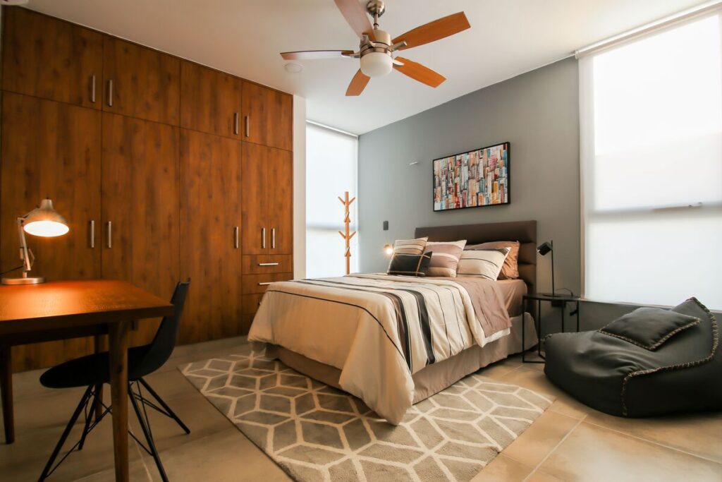 Ma maison ne redescend pas en température le soir : les vraies causes et comment la rafraîchir 4 Un brasseur d'air de plafond en bois design en fonctionnement dans une chambre à coucher lumineuse.