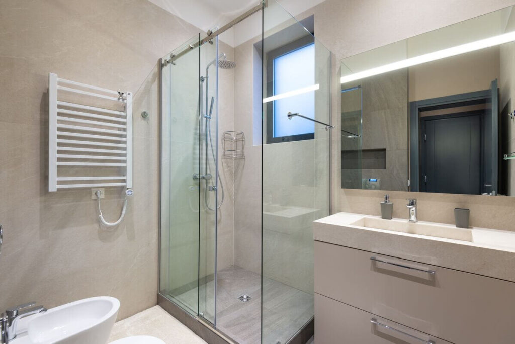 Porte de douche coulissante en verre transparent installée dans une petite salle de bain moderne.