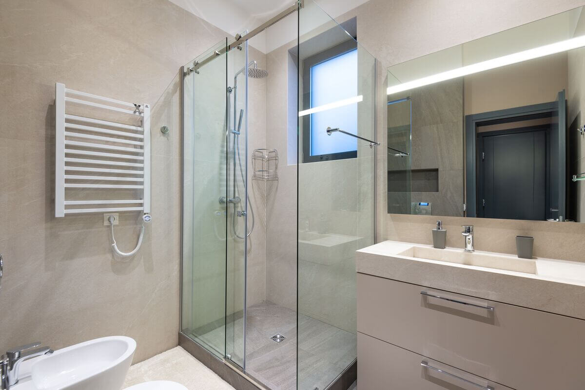 Porte de douche coulissante en verre transparent installée dans une petite salle de bain moderne.