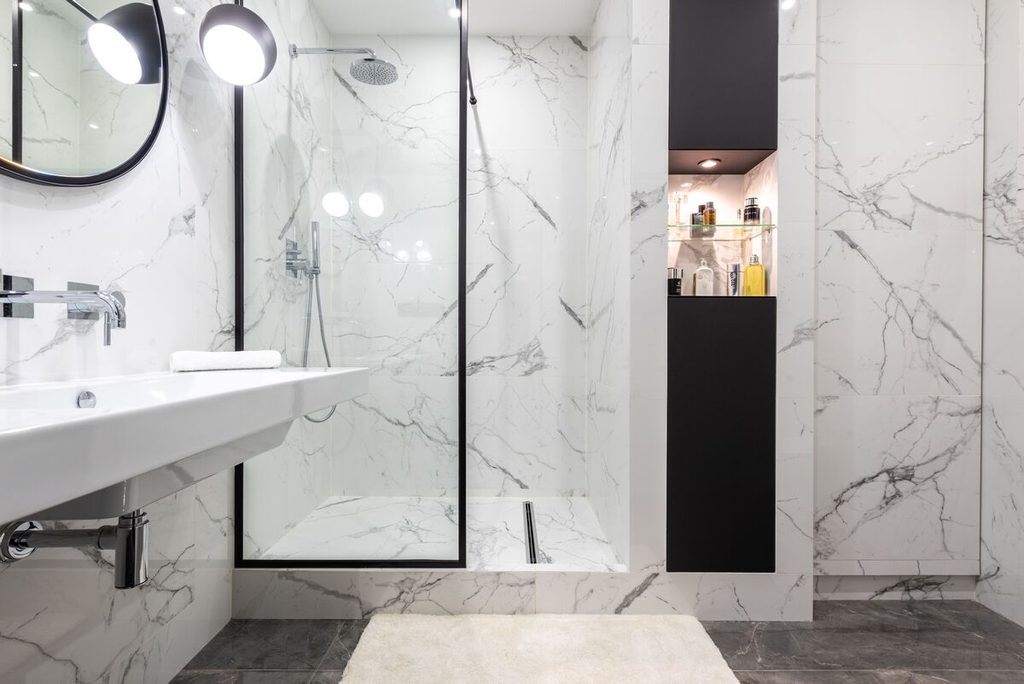 Porte de douche battante vitrée avec profilé noir offrant une large ouverture d'accès.