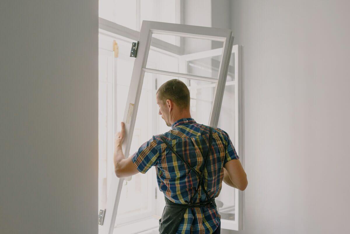 Artisan installant une fenêtre isolante pour étanchéifier le logement contre le froid.