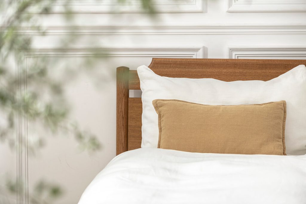 Lit en chêne massif habillé de draps en lin naturel dans une ambiance sobre et épurée.