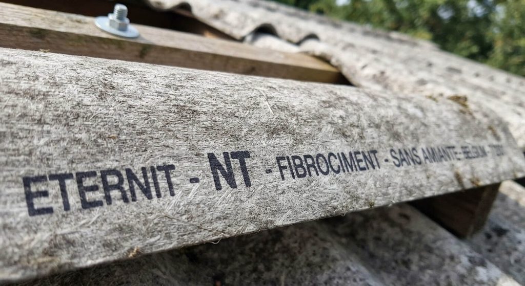 Reconnaître une plaque fibro-ciment amiante : 5 indices 3 Gros plan sur une plaque de fibrociment affichant la mention NT garantissant l'absence d'amiante.