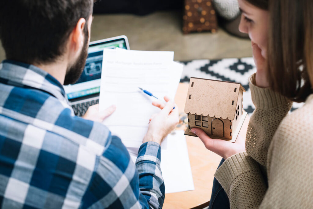 Assurance pour sa maison : comment bien la choisir sans payer trop cher ? 2 Propriétaire signant un contrat d'assurance multirisque habitation pour sa maison individuelle.