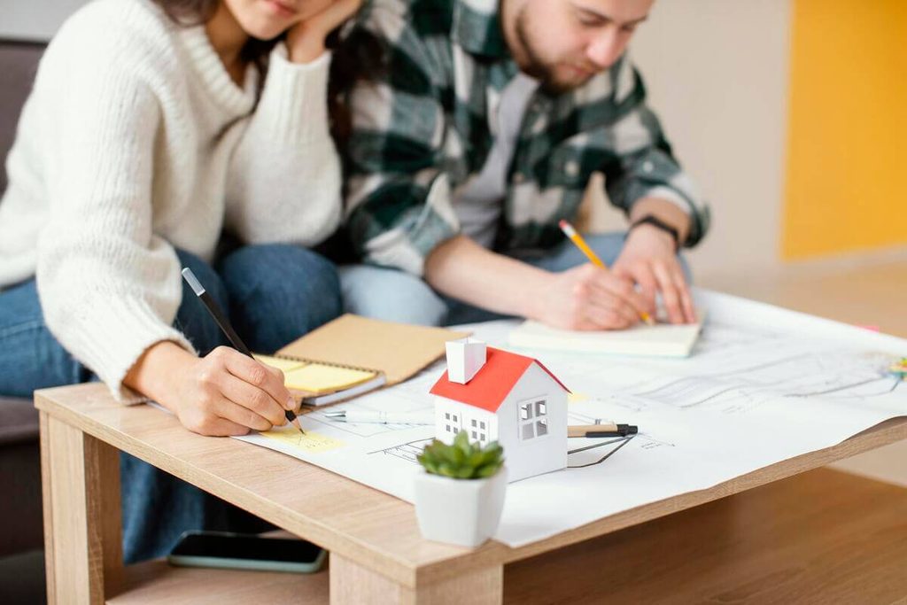 CCMI : ce que le contrat couvre, prix, garanties et pièges 3 Futurs propriétaires signant les clauses d'un contrat de construction de maison individuelle (CCMI) en agence.