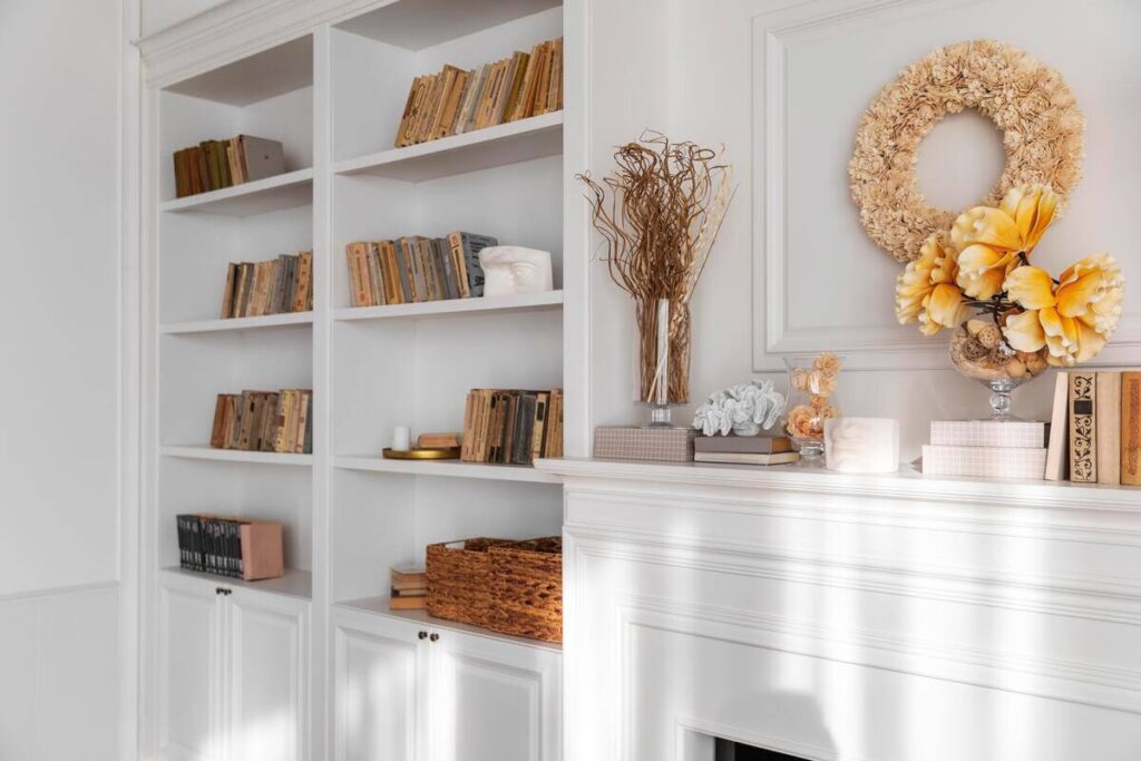 Grande étagère bibliothèque en bois clair et métal aménagée sur tout un pan de mur dans un salon moderne.