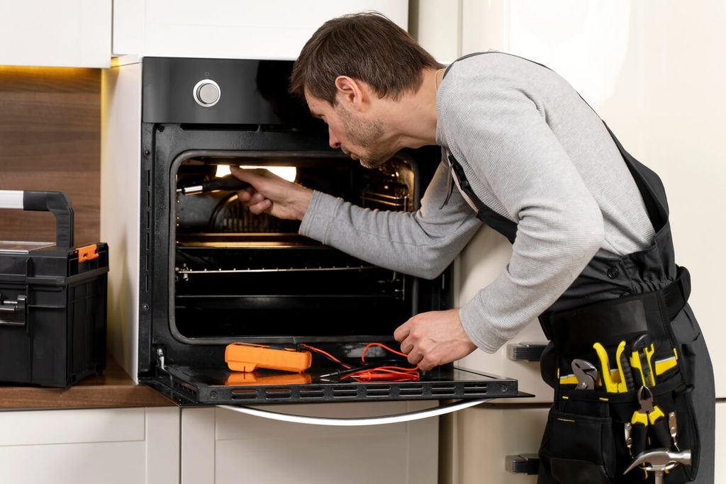 Four qui ne chauffe pas assez : causes, diagnostic et solutions 3 Démontage de la résistance inférieure de sole à l'arrière d'un four de cuisine.