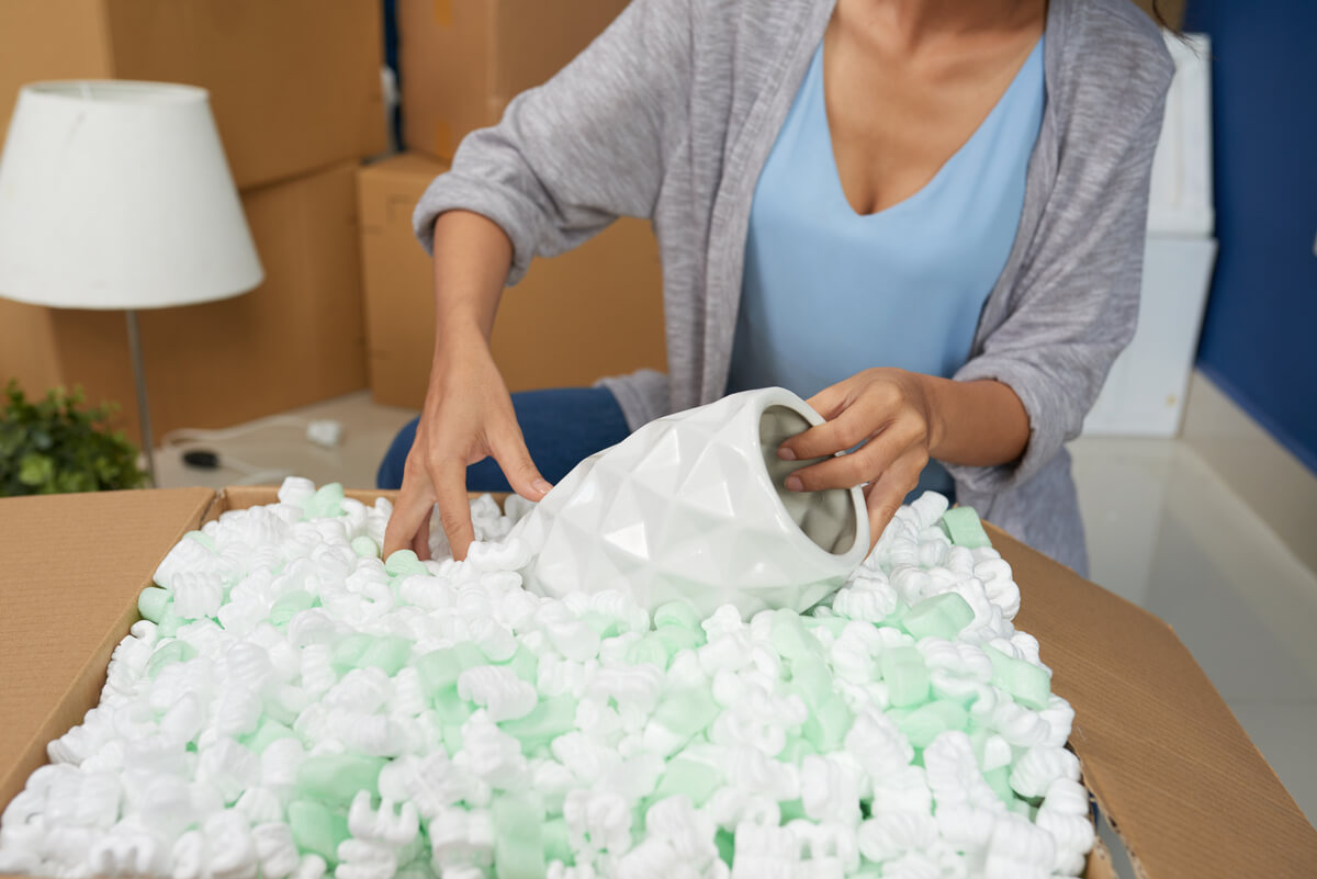 Emballage minutieux d'assiettes et verres avec du papier bulle pour préparer un carton de déménagement.