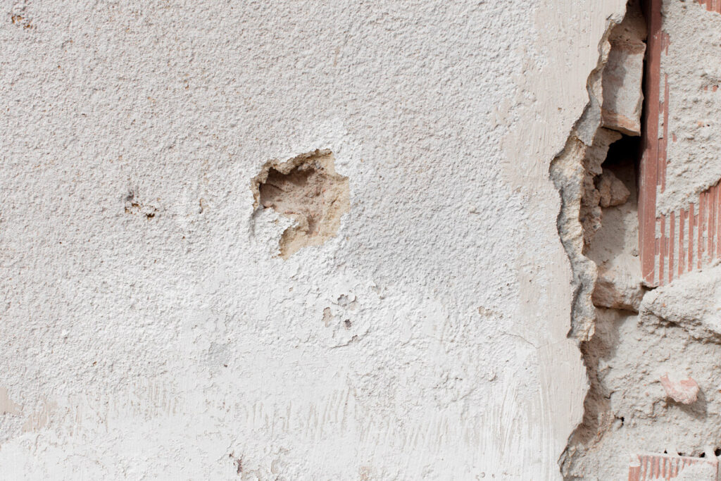Importantes fissures en escalier sur la façade d'une maison individuelle liées au retrait-gonflement des argiles.