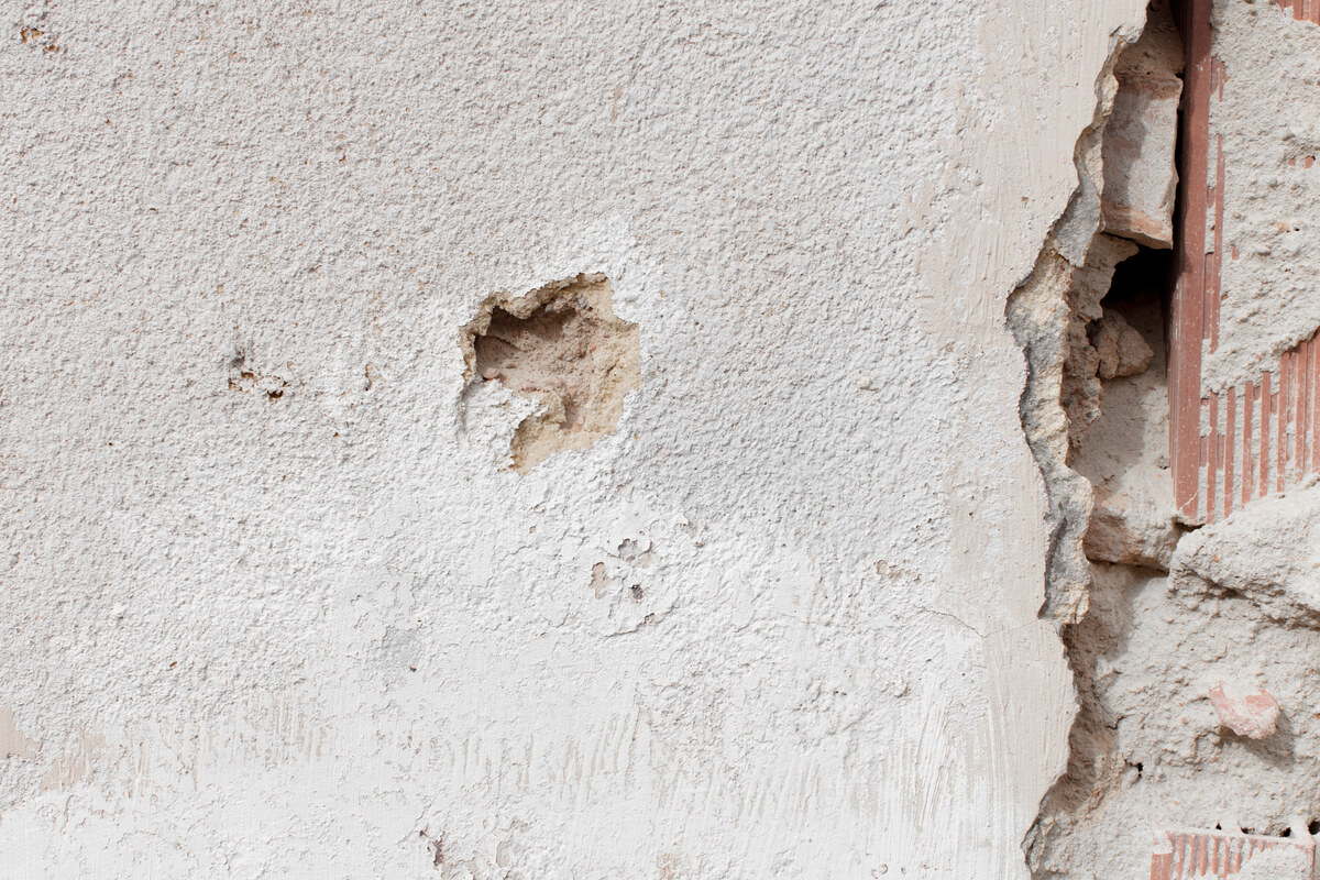 Importantes fissures en escalier sur la façade d'une maison individuelle liées au retrait-gonflement des argiles.
