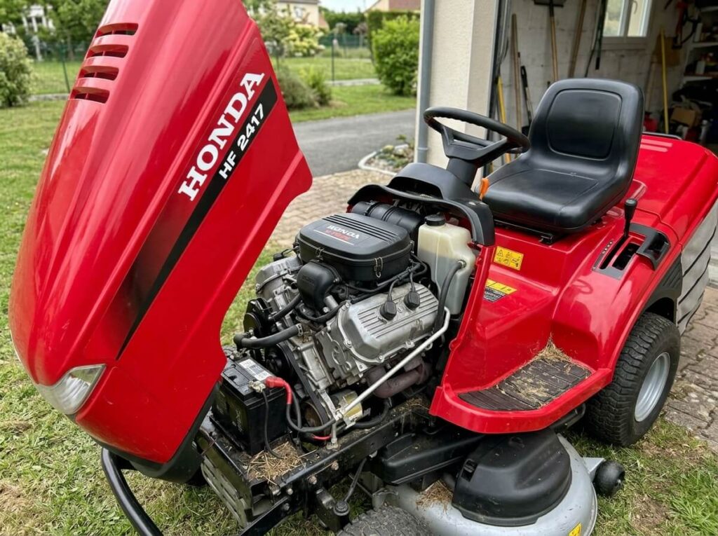 Problème de tracteur tondeuse Honda 2417 : pannes, boîte hydrostatique et démarrage 2 Capot ouvert d'une autoportée Honda HF 2417 montrant le moteur bicylindre V-Twin.